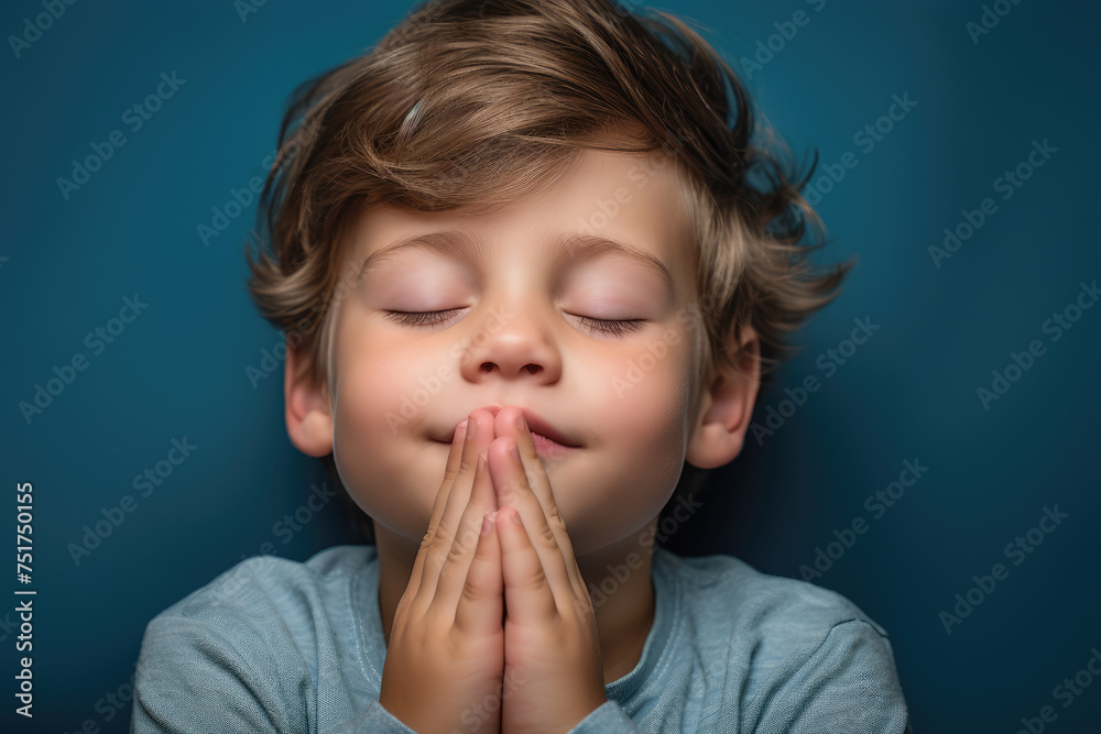 Young boy with closed eyes and clasped hands, deeply immersed in prayer or meditation, radiates peaceful contemplation, blue background Young boy with closed eyes and clasped hands, deeply immersed in prayer or meditation, radiates peaceful contemplation, blue background