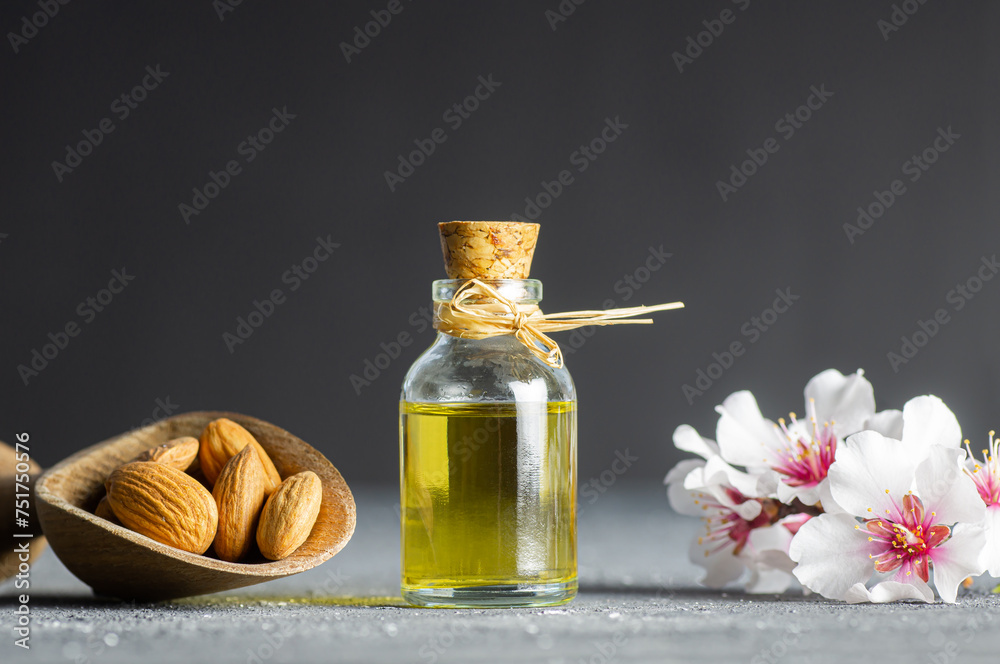 Glass bottle of Almond oil and almond nuts , almonds with almond tree flowers on table. Almond background concept with copy space Glass bottle of Almond oil and almond nuts , almonds with almond tree flowers on table. Almond background concept with copy space