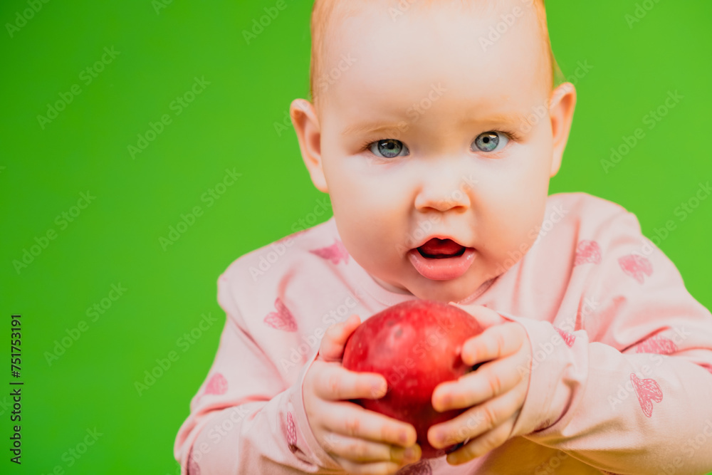Baby Eating Red Apple. A baby is sitting holding an apple and taking a bite. The child seems to be enjoying the healthy snack while sitting in a relaxed position.