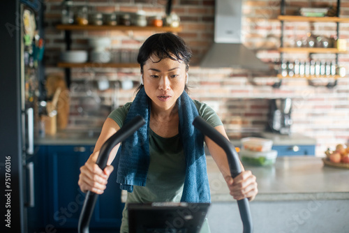 Young Asian woman on a exercise bike at home photo