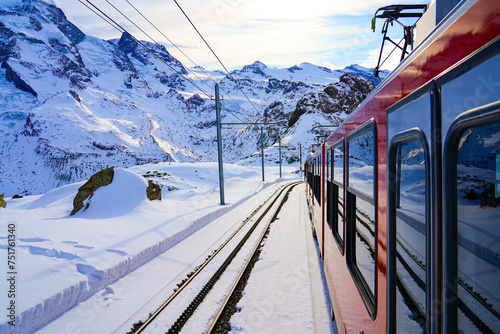 View of the snow-capped mountains from a window of the cogwheel train of the Gornergrat Railway descending towards Zermatt in the Swiss Alps in winter, Canton of Valais, Switzerland photo