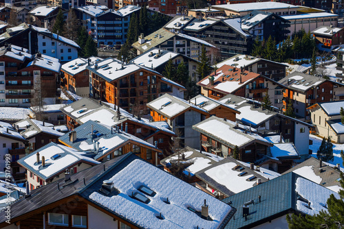 Snow-covered rooftops of Zermatt in the Swiss Alps in winter - Idyllic landscape with wooden chalets in a famous ski resorts towered by the Matterhorn