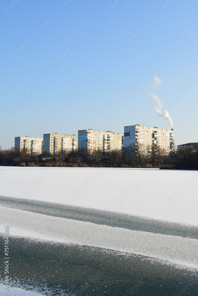 Winter landscape of a frozen lake. View of Soviet buildings. Vertical image. 