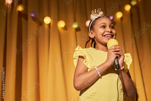 Waist up portrait of smiling Black girl speaking to microphone while giving home concert and show performance copy space 