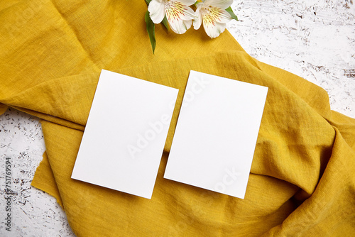 Blank invitation cards mockup with alstroemeria on golden textile, top view, flat lay