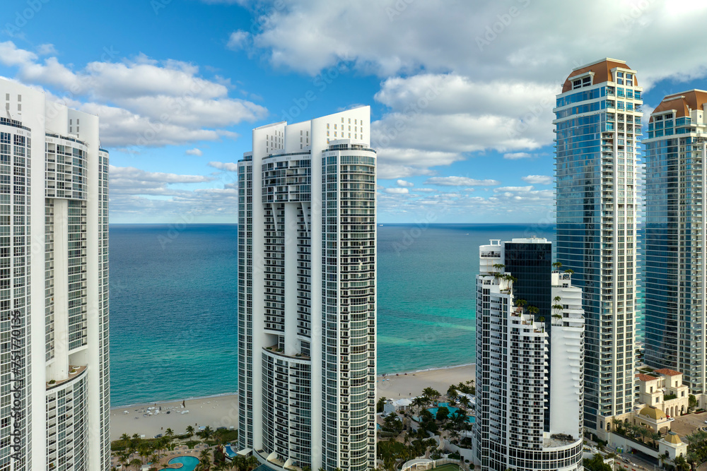 View from above of luxurious highrise hotels and condos on Atlantic ocean shore in Sunny Isles Beach city. American tourism infrastructure in southern Florida - obrazy, fototapety, plakaty 