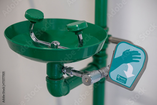 Green emergency eyewash station with a push lever, designed for industrial safety and rapid eye decontamination in hazardous environments. photo