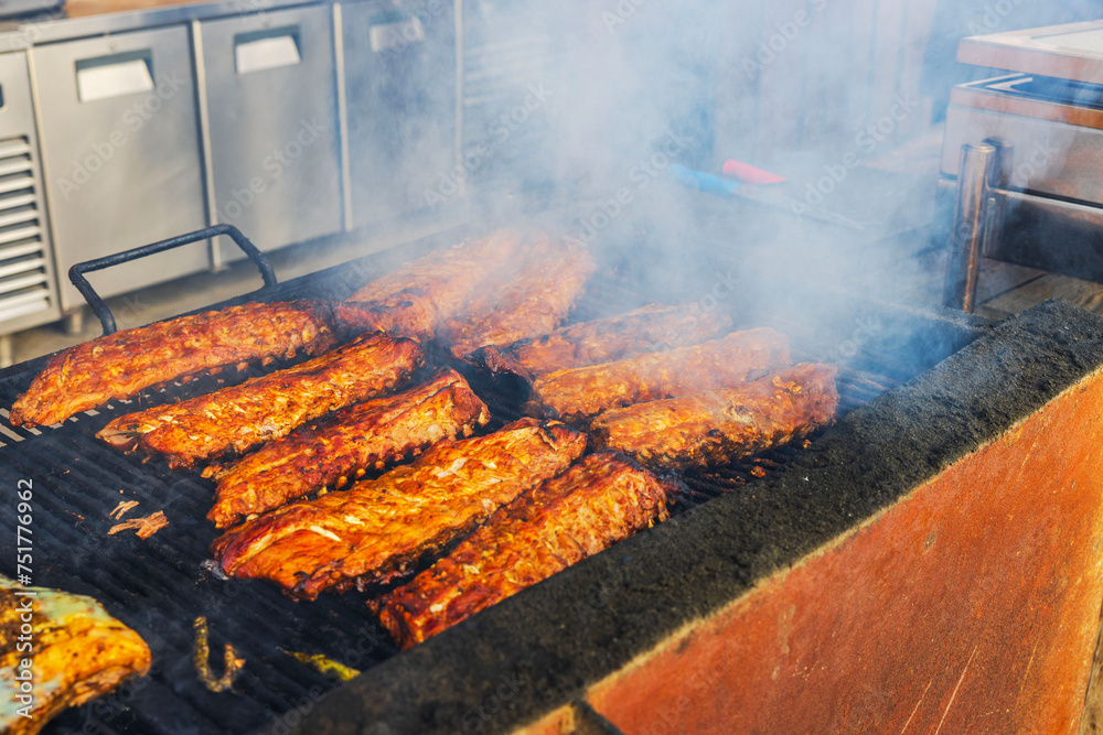 Close-up view of grilling pork ribs outdoors at a restaurant under the open sky. Curacao. Close-up view of grilling pork ribs outdoors at a restaurant under the open sky. Curacao.