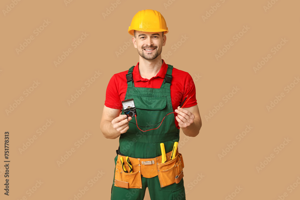 Portrait of male electrician with multimeter on beige background