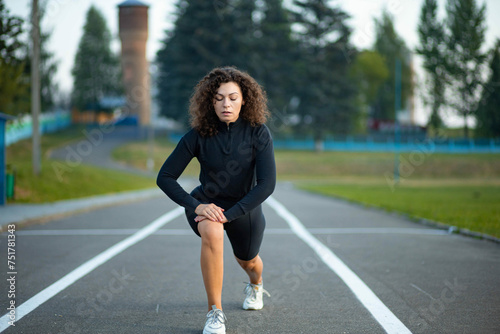 young curly woman athlete jogging at the stadium in summer
