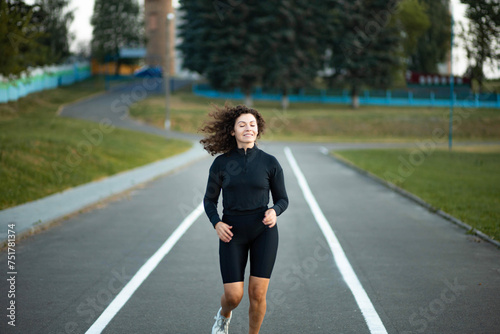 young woman jogging at the stadium. Curly-haired sportswoman jogging in the morning.