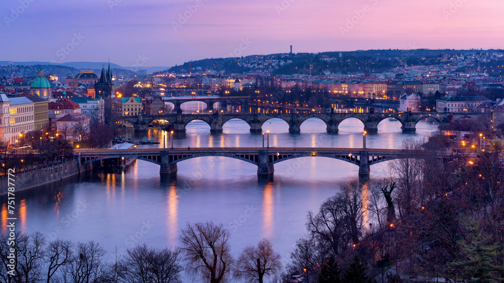 Glowing twilight over Prague, with illuminated bridges arching over a peaceful river, surrounded by classical architecture and tree silhouettes