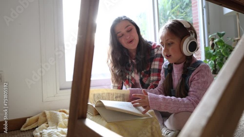 Granddaughter girl with her grandmother reading together in the living room of their house