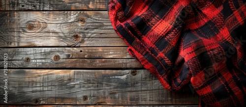 A red and black plaid blanket is laid out neatly on a wooden floor, creating a cozy and rustic feel.