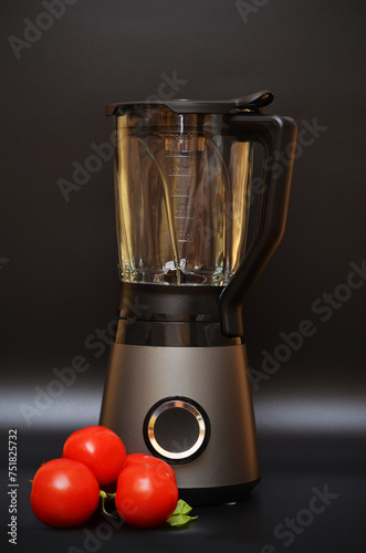 kitchen blender on a black background and tomatoes nearby