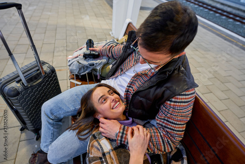 In the comfort of each others company, a couple engages in a playful conversation while waiting for their train, their connection evident.