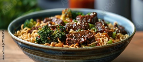 A bowl filled with savory noodles topped with tender beef slices and vibrant broccoli pieces in a delicious sauce. photo