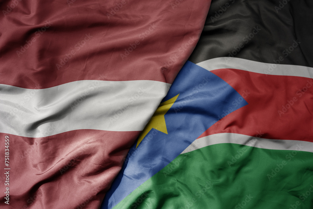 big waving national colorful flag of south sudan and national flag of latvia.
