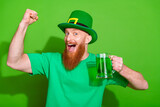 Photo of overjoyed funky person hold st patrick drink mug raise fist isolated on green color background