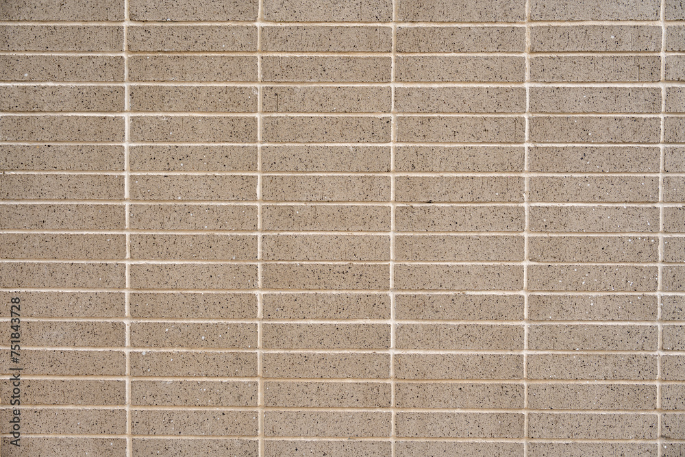 Fototapeta premium Wall covered with beige symmetrical and minimalistic tiles. Square and smooth material separated by light-colored grout lines. Concept of texture and pattern