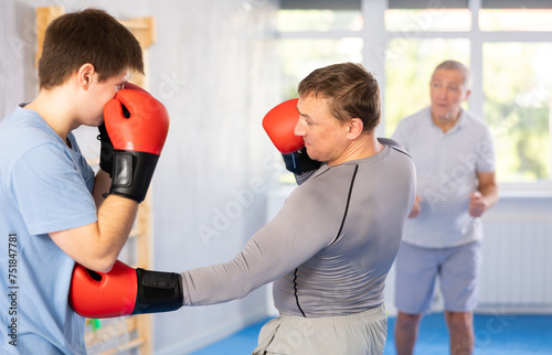 Adult man training boxing punches with sparring partner in studio