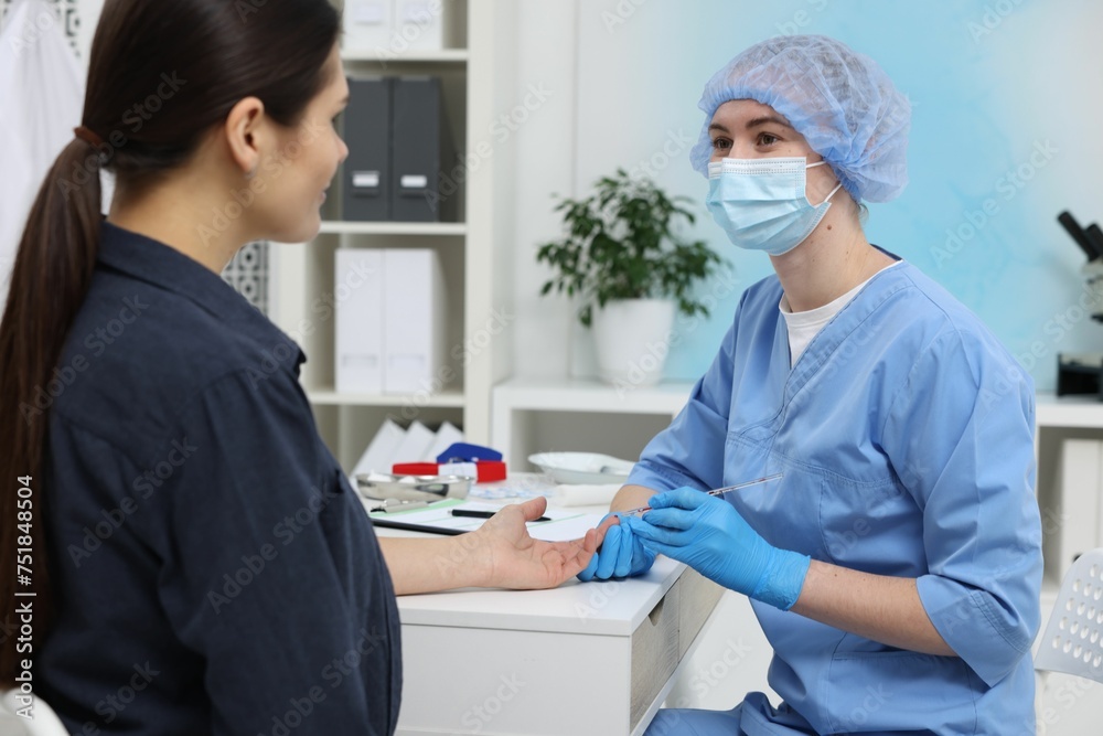 Fototapeta premium Laboratory testing. Doctor taking blood sample from patient at white table in hospital