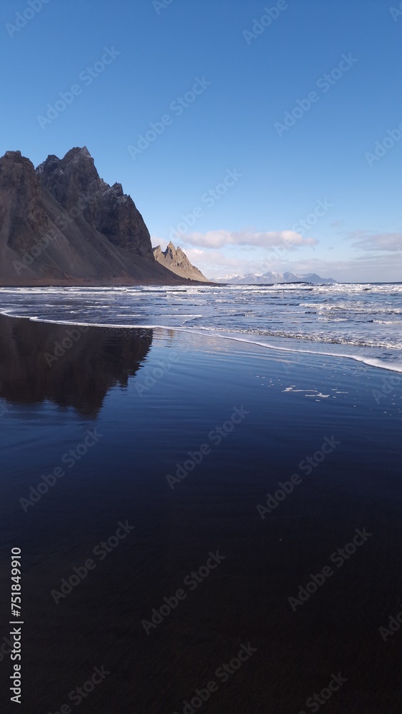Massive vestrahorn mountains connect with ocean, fantastic nordic setting with unique black sand beach. Icelandic stokksnes peninsula with huge cliffs and hills, breathtaking scenic route.