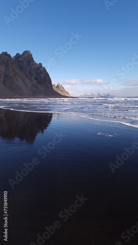 Massive vestrahorn mountains connect with ocean, fantastic nordic setting with unique black sand beach. Icelandic stokksnes peninsula with huge cliffs and hills, breathtaking scenic route. © DC Studio