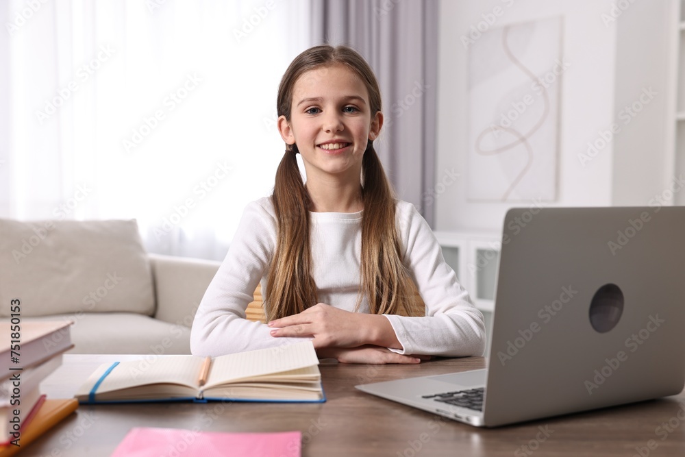 E-learning. Cute girl using laptop during online lesson at table indoors E-learning. Cute girl using laptop during online lesson at table indoors