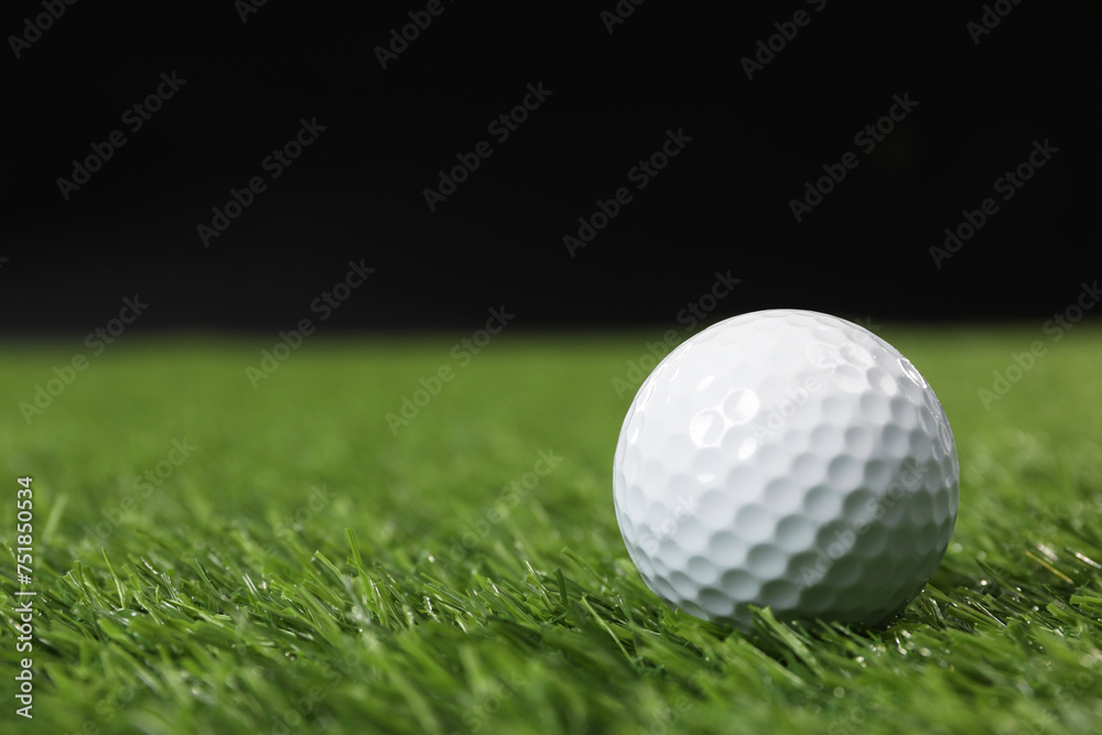 Golf ball on green grass against black background, space for text Golf ball on green grass against black background, space for text