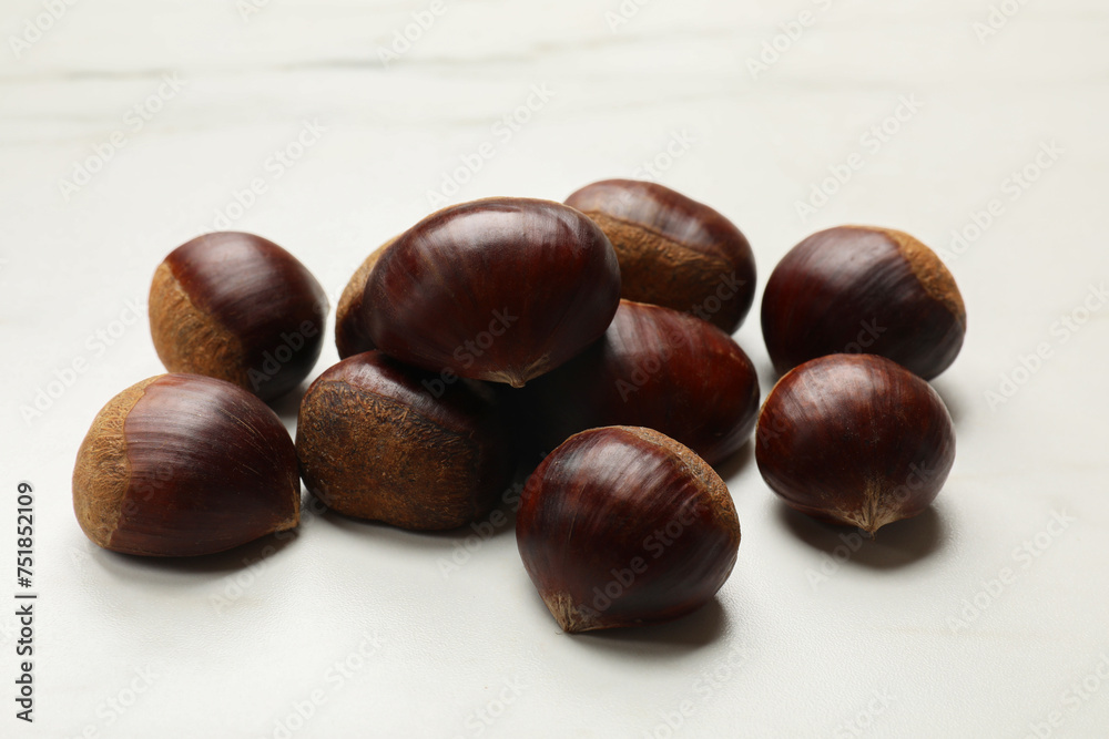Sweet fresh edible chestnuts on white table, closeup Sweet fresh edible chestnuts on white table, closeup