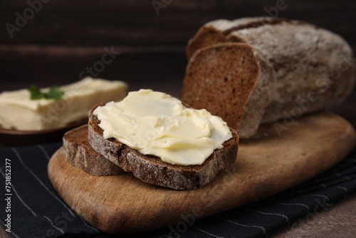 Slices of tasty bread with butter on grey textured table, closeup