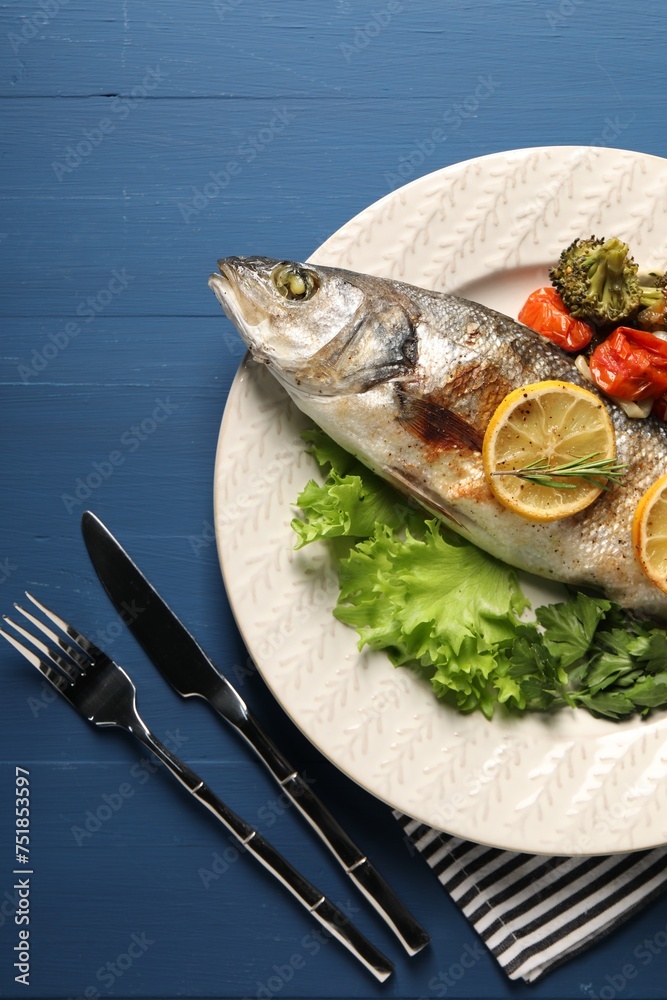 Delicious baked fish and vegetables served on blue wooden table, top view Delicious baked fish and vegetables served on blue wooden table, top view