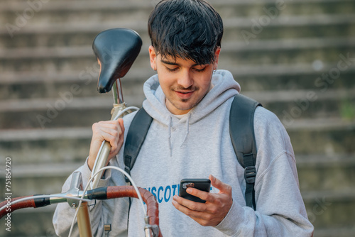 student with mobile phone carrying the bicycle