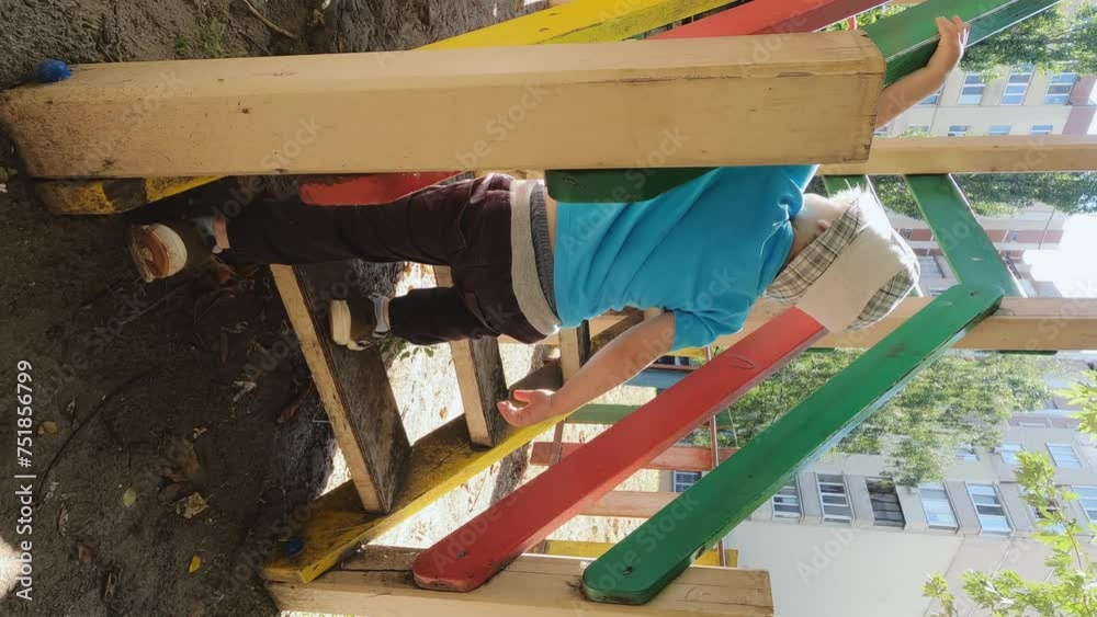 Vertical video of a boy walking down the steps of a playground ...
