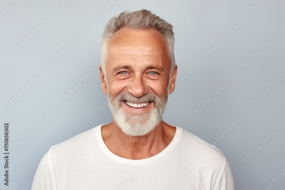 Portrait of a happy senior man smiling at camera against grey background Portrait of a happy senior man smiling at camera against grey background