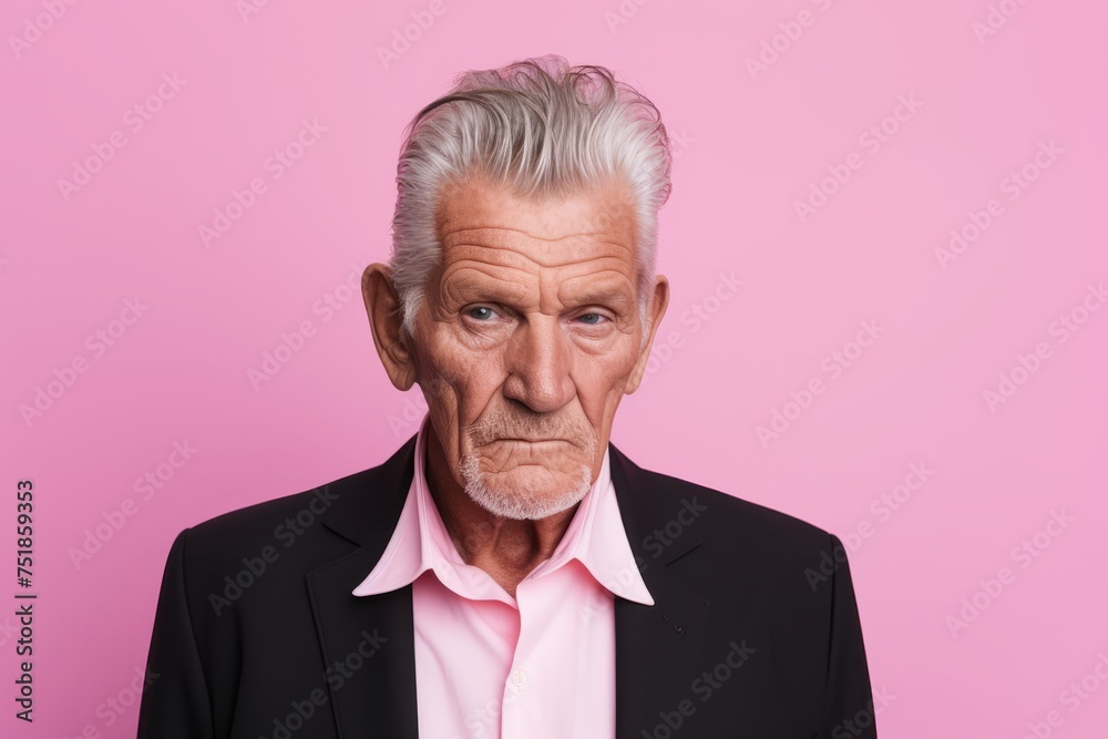 Portrait of an elderly man with grey hair wearing a suit and looking at the camera against a pink background Portrait of an elderly man with grey hair wearing a suit and looking at the camera against a pink background