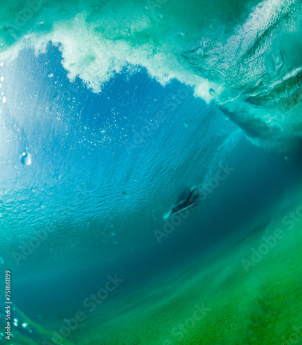 An underwater shot capturing a surfer gliding through the emerald depths of a wave, showcasing the interplay of light and water photo