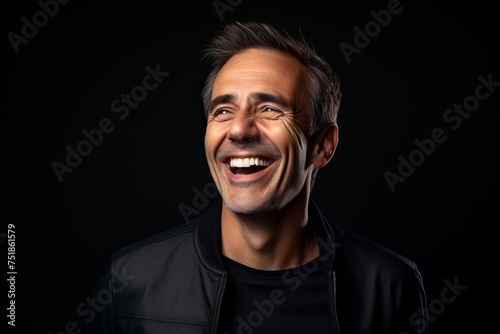 Portrait of a handsome middle-aged man laughing over black background.