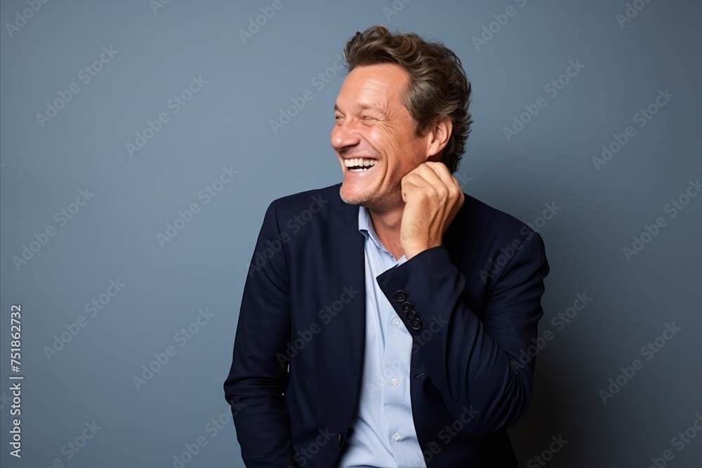 Portrait of a happy mature man laughing against a blue background.