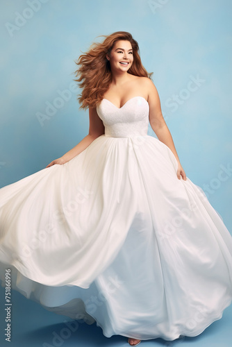 Young redhead full-figured bride in a flowing white wedding dress in blue backdrop. Concept of bridal joy, natural beauty, grace, femininity, and elegant simplicity.