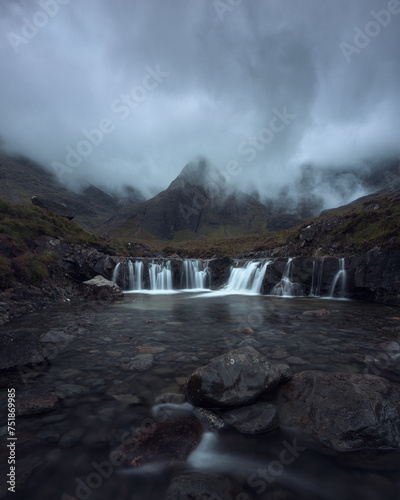 Morning view of a river with a waterfall and a cloud-shrouded mountain peak. Scenic landscape with trickling waterfall in the morning. Fairy Pools, Isle of Skye, Scottish Highlands, UK