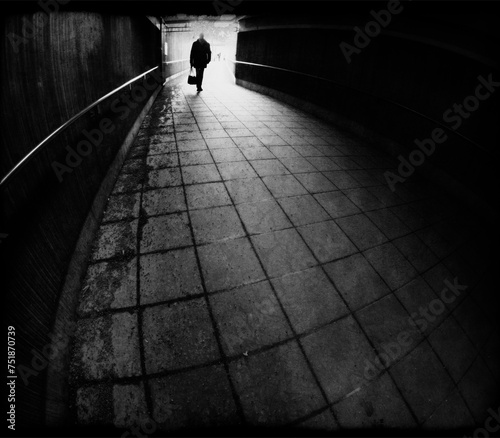 Silhouette of man entering a dark tunnel in black and white