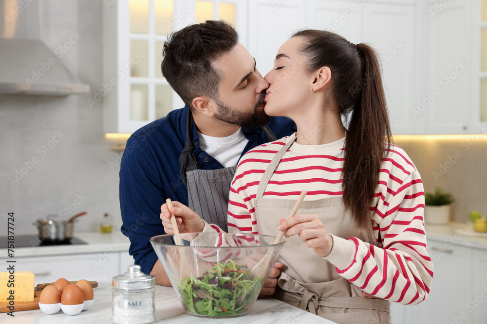 Lovely couple kissing while cooking in kitchen