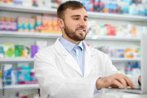 Professional pharmacist working on laptop in modern drugstore