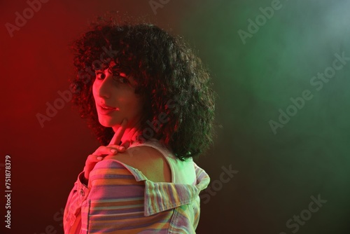 Beautiful young woman posing on color background in neon lights. Space for text