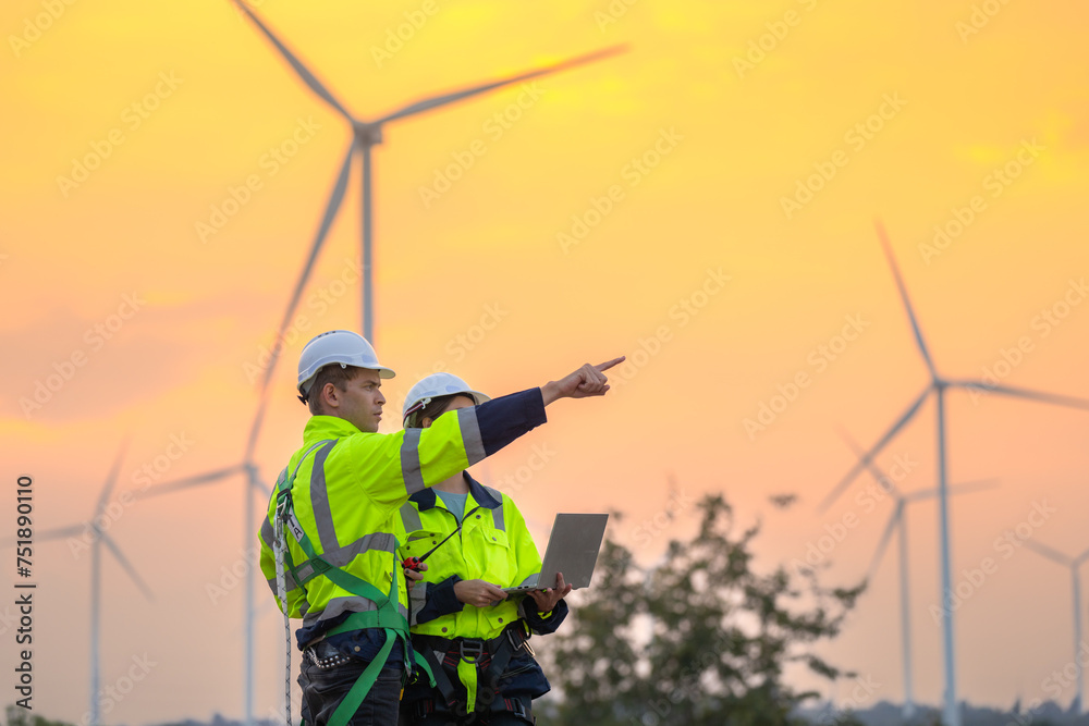 Team Engineers men and woman checking and inspecting on construction with sunset sky. people operation. Wind turbine for electrical of clean energy and environment. Industrial of sustainable. Team Engineers men and woman checking and inspecting on construction with sunset sky. people operation. Wind turbine for electrical of clean energy and environment. Industrial of sustainable.