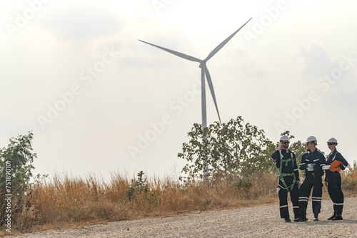 Engineers man and woman inspecting construction of WIND TURBINE FARM. WIND TURBINE with an energy storage system operated by Super Energy Corporation. Workers Meeting to check AROUND THE AREA.