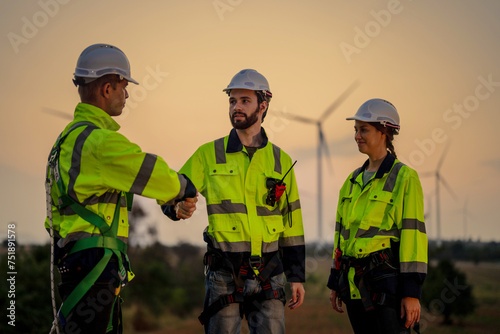 Team Engineers men and woman celebrating on construction site with sunset sky. people operation. Wind turbine for electrical of clean energy and environment. Industrial of sustainable.