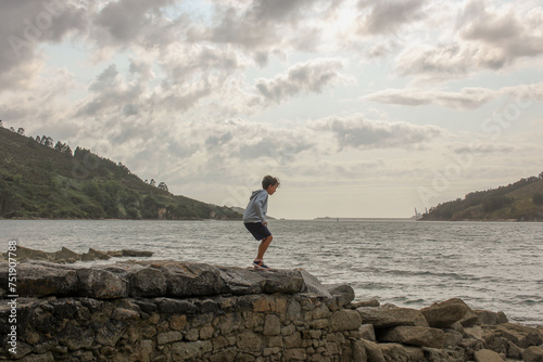 boy over a stone wall in a beach